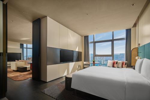 Un dormitorio con una gran cama blanca y una sala de estar. en Hotel Indigo Zhuhai Xiangzhou by IHG, en Zhuhai