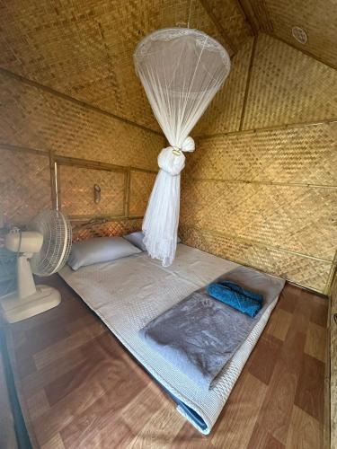 a small bed in a room with a fan at มีสุข ฟาร์มสเตย์ in Lop Buri