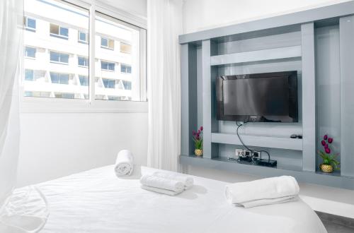 Habitación blanca con TV y cama en מילה דירות אירוח - Skyline Eilat, en Eilat