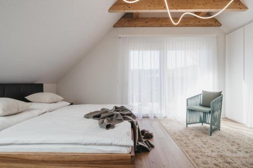 a bedroom with a bed and a chair and a window at Das Dietrich - Landhaus 62 in Leibnitz