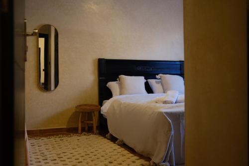 a bedroom with a bed with white sheets and a mirror at Catamaran Surf House in Imi Ouaddar