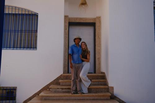 Un uomo e una donna in piedi su qualche scala di Catamaran Surf House a Agadir nʼ Aït Sa