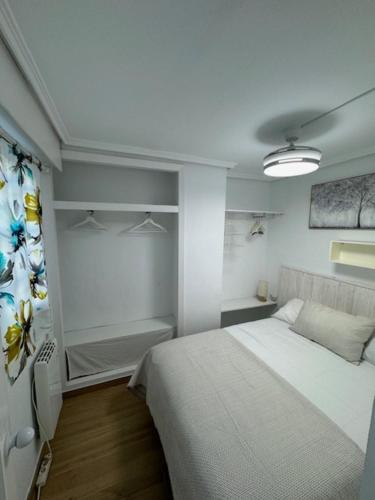 een slaapkamer met een wit bed in een kamer bij Apartamento Arenal 1a Linea de Playa in Cullera