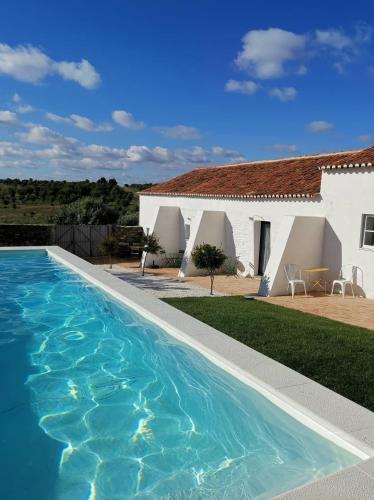 a villa with a swimming pool in front of a house at Casa no Montinho in Ourique