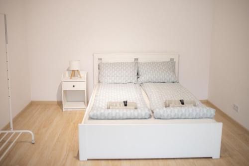 a white bed with two pillows and a night stand at Domek na Lipowej in Stare Miasto