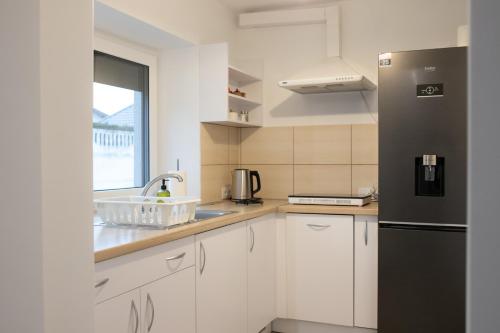 a kitchen with white cabinets and a black refrigerator at Domek na Lipowej in Stare Miasto