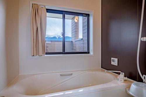 a bath tub in a bathroom with a window at SAKURA FUJI in Fujikawaguchiko