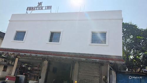 Swastiik Inn的白色的建筑,上面有两扇窗户