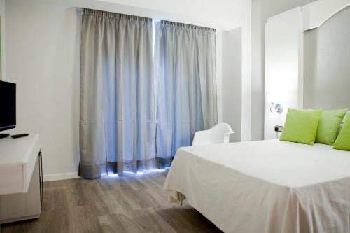 a white bedroom with a bed and a television at Mir Octavio in Algeciras
