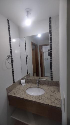 a bathroom with a sink and a large mirror at Suite no Boulevard suite hotel in Caldas Novas