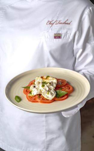 eine Person, die einen Teller mit Nahrung darauf hält in der Unterkunft DoubleTree by Hilton Madinah Gate in Medina