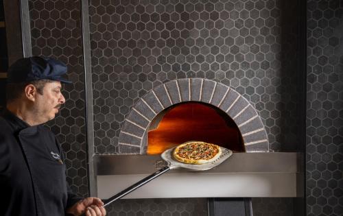 Ein Mann steckt eine Pizza in einen Ofen. in der Unterkunft DoubleTree by Hilton Madinah Gate in Medina