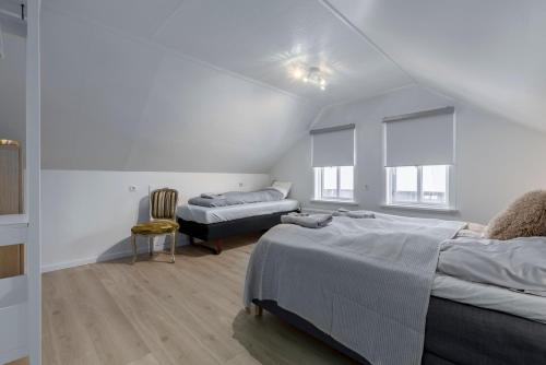 Una habitación blanca con dos camas y una silla. en Two story townhouse apartment in old town Reykjavik, en Reikiavik