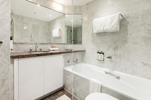 Un baño blanco con bañera y lavabo. en Modern Apartments Step from Quay west Sebel, en Sídney