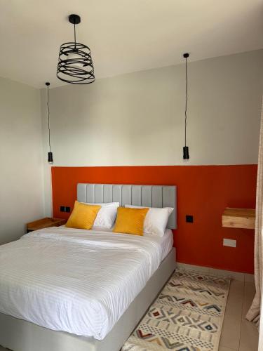 a bed with orange and white pillows in a room at SpotOne Suites in Nyeri