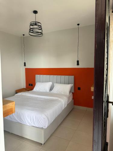 a bed in a bedroom with an orange and white wall at SpotOne Suites in Nyeri