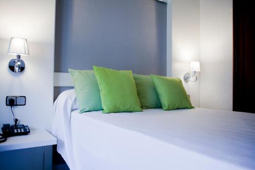 a bedroom with a white bed with green pillows at Mir Octavio in Algeciras