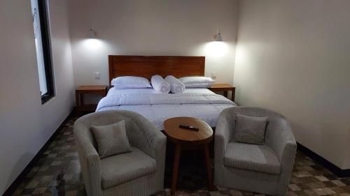 a bedroom with a bed with two chairs and a table at See Sea Hostel & Resto in Jepara