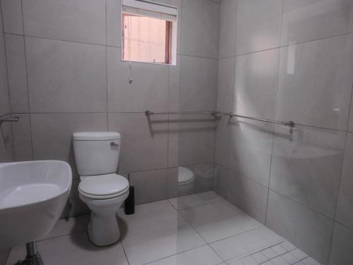 a white bathroom with a toilet and a sink at Uitspan No 5 in St Lucia