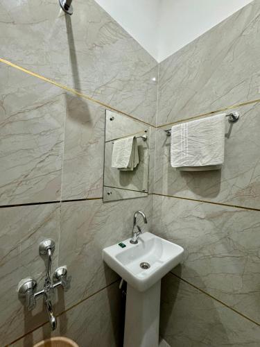 a bathroom with a sink and a mirror and towels at hotelsiyashreeram in Orchha