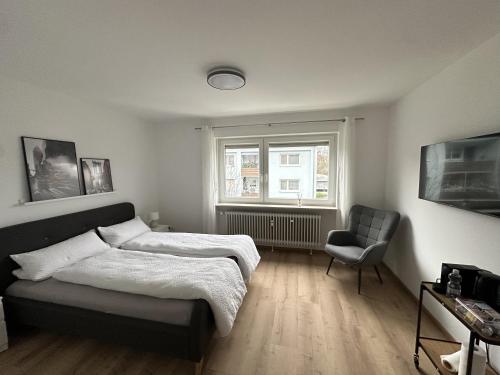 um quarto com uma cama, uma cadeira e uma janela em Modernes 2-Zimmer Apartment in Aschaffenburg em Aschaffenburg