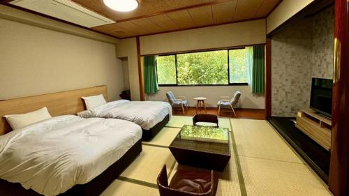 a hotel room with two beds and a television at Ureshino Onsen Yusyuku Sarayama in Ureshino
