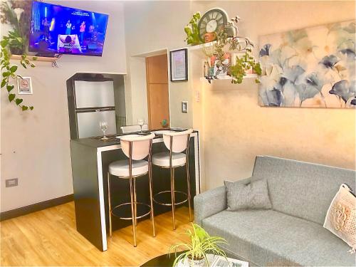 a living room with a couch and a bar with stools at Alquiler por dia "Como en Casa" Caseros, cerca de Palomar y Hurlingham in Caseros