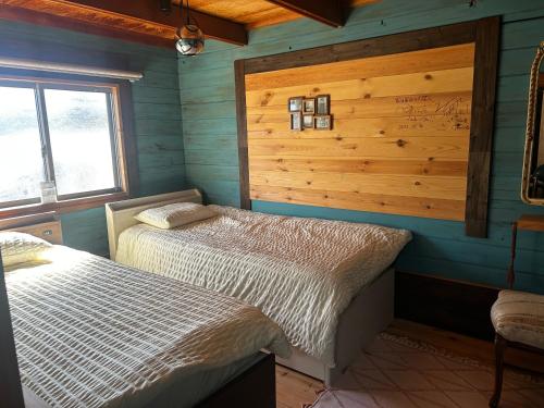 a bedroom with two beds in a room with wooden walls at Smith's island Hut in Hinase