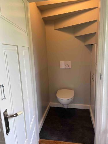 a bathroom with a toilet in a room with stairs at Huisje weltevreden in Ekshärad