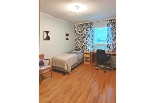 a bedroom with a bed and a desk and a window at Kotimaailma Woody 3 in Lahti