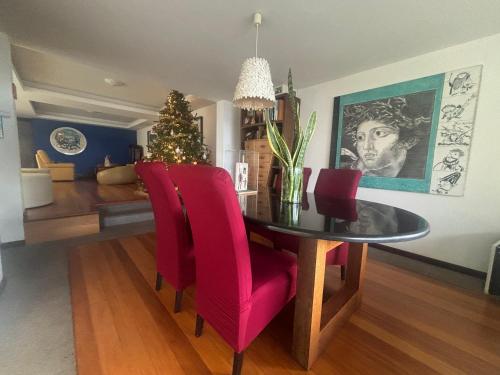 a dining room table with red chairs and a christmas tree at Suite Bela Vigia 4 in Jardim do Mar