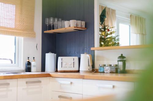 a kitchen with white cabinets and a christmas tree at Secluded Sanctuary On The River in Christchurch
