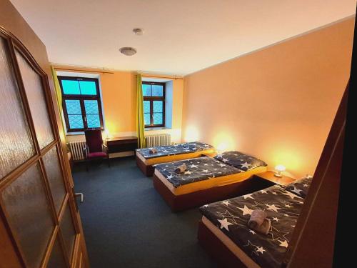 a room with three beds and a chair in it at Hostinec Lovecký zámeček in Olešnice v Orlických horách