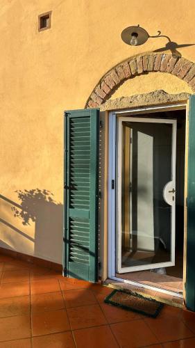 an open door with a green shutter next to a building at Poggiarello 10 in Guardistallo