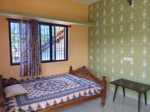 ein Schlafzimmer mit Bett, Tisch und Fenstern in der Unterkunft Farm House Shetgeri in Ankola
