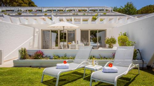 a white patio with two chairs and an umbrella at Quinta do Lago Country Club in Quinta do Lago