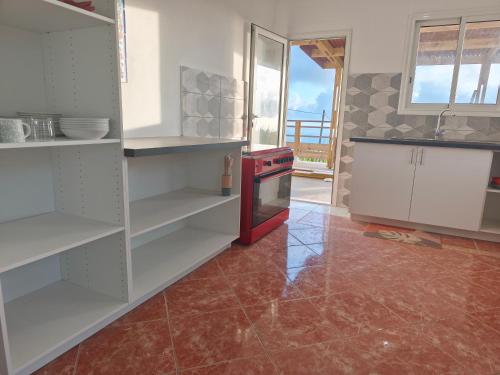 a kitchen with white cabinets and a red stove at Kaz Lorizon in Petite Île