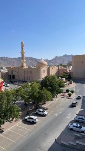 Qala View Inn في نزوى‎: شارع به سيارات متوقفة في موقف سيارات به مسجد