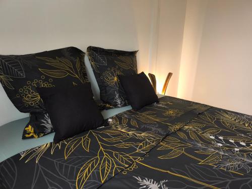 a bed with black and gold sheets and pillows at Kaz Lorizon in Petite Île