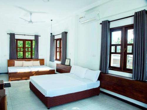 a bedroom with a large bed and two windows at Heavens Talpe in Talpe