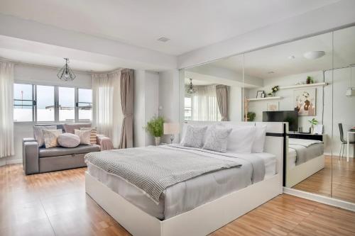 a white bedroom with a large bed and a couch at Cozy A at Nimman Studio Room in Condominium in Chiang Mai