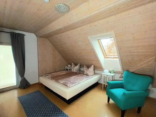 a bedroom with a bed and a blue chair at Gästehaus am Hofberg in Thalmässing