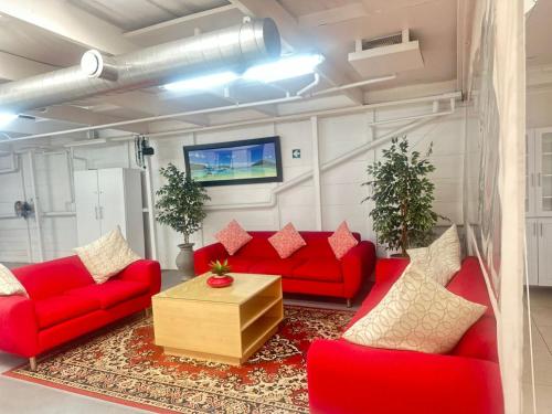 Surrey B&B في Surrey Estate: غرفة معيشة مع أرائك حمراء وتلفزيون