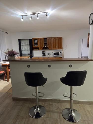 a kitchen with two bar stools in front of a counter at Willa MARSI in Stalowa Wola