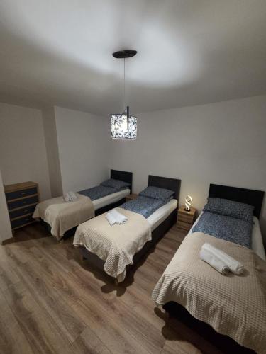 a room with three beds and a chandelier at Willa MARSI in Stalowa Wola