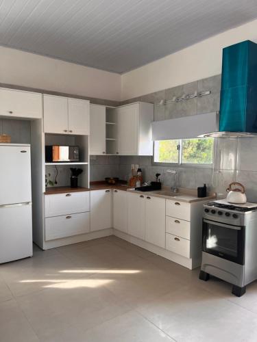 Una cocina con gabinetes blancos y un horno de estufa. en Pindo, en Chuy