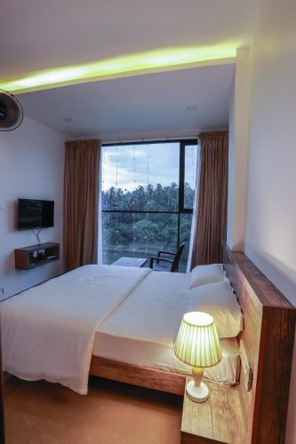 a bedroom with a large bed and a large window at Atholi Residency in Mukkam