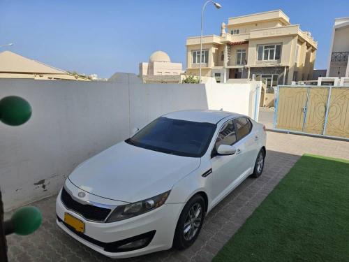un coche blanco estacionado junto a una pared blanca en DrOmid, en Maţār as Sīb ad Duwalī