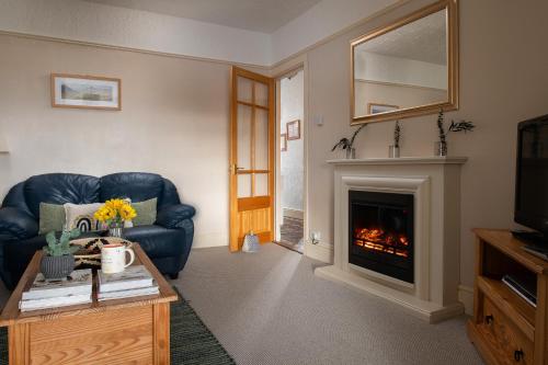 a living room with a blue couch and a fireplace at Heligog at Deanfield House Moelfre Sea view adult only appartment in Moelfre in Moelfre