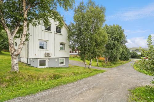 House in the middle of Lofoten - Leknes في ليكنيز: بيت ابيض على طريق فيه اشجار